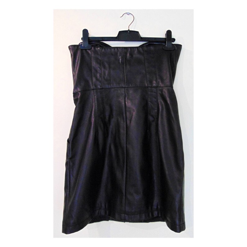 May include: A black strapless dress made of faux leather. The dress has a fitted bodice and a slightly flared skirt.