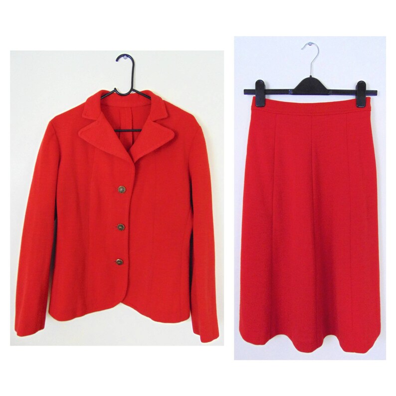 May include: A red blazer and skirt suit. The blazer has a notched collar and three buttons. The skirt is A-line and knee-length.