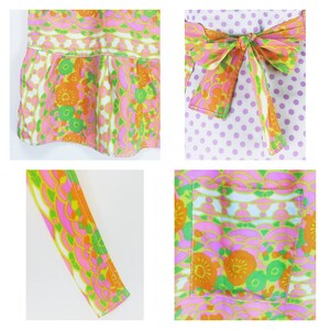 May include: A pink, green, and orange floral print apron with a white polka dot bow tie. The apron has a large pocket on the front and a ruffle at the bottom.