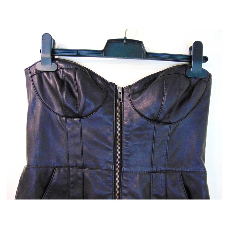 May include: A black strapless faux leather dress with a zipper down the front. The dress has a fitted bodice and a slightly flared skirt.
