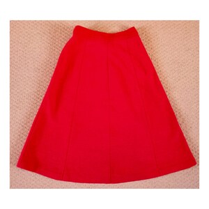May include: A bright red A-line skirt with a simple design. The skirt is made of a smooth, lightweight fabric.