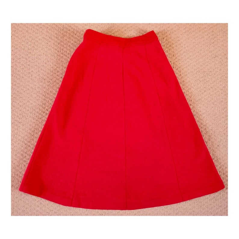 May include: A bright red A-line skirt with a simple design. The skirt is made of a smooth, lightweight fabric.