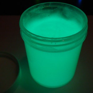 May include: A clear plastic jar filled with a bright green glowing liquid. The jar has a white lid.
