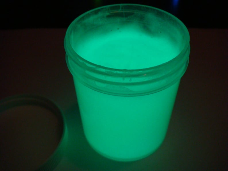May include: A clear plastic jar filled with a bright green glowing liquid. The jar has a white lid.