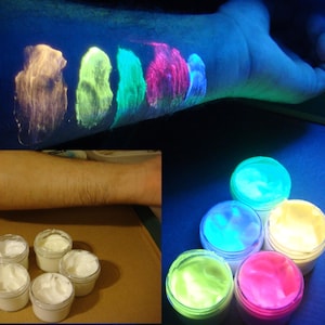 Könnte beinhalten: Sechs kleine Gläser mit Neon-Leuchtfarbe, die im Dunkeln leuchtet. Die Farbe ist in verschiedenen Farben, darunter Gelb, Grün, Blau, Pink und Weiß. Die Gläser sind in einem Kreis auf einer dunklen Oberfläche angeordnet.
