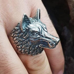 Könnte beinhalten: Ein silberner Wolfskopfring. Der Ring ist mit Fell verziert und hat ein realistisches Wolfskopfdesign.