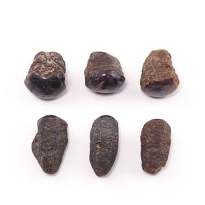 May include: Six individual dark brown, rough-textured stones arranged in two rows of three. Each stone displays an irregular, organic shape with a matte, weathered surface appearance. The stones vary slightly in size and form, showing natural variations in their dark, earthy coloration and pitted, uneven exterior textures.