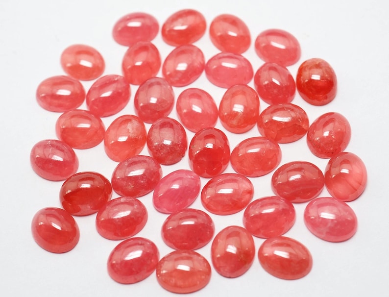 K&ouml;nnte beinhalten: Eine Sammlung von 30 ovalen, rosafarbenen, halbedlen Edelsteinen. Die Steine sind glatt und poliert und haben einen leichten Glanz.