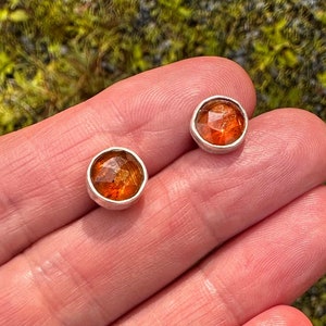 Puede incluir: Un par de pendientes de bot&oacute;n de plata con piedras redondas de color marr&oacute;n anaranjado.