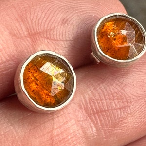 Puede incluir: Un par de pendientes de plata con cabujones de piedras preciosas de color naranja. Las piedras preciosas tienen un corte facetado y est&aacute;n engastadas en un engaste de bisel.