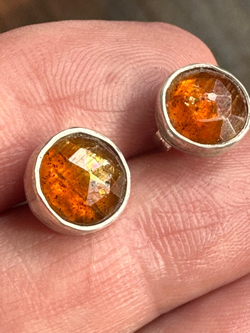 Puede incluir: Un par de pendientes de plata con cabujones de piedras preciosas de color naranja. Las piedras preciosas tienen un corte facetado y est&aacute;n engastadas en un engaste de bisel.