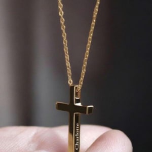 Può includere: Una collana con catena d'oro con un ciondolo a forma di croce d'oro. La croce ha inciso il nome "Charlotte".