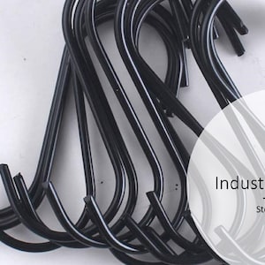 May include: A close-up of a pile of black metal S-hooks. The hooks are all the same size and shape, and they are arranged in a random pattern. The text "Industrial S-Hook Stout & Burg" is visible in the image.