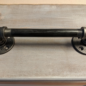 May include: Black metal pipe handle with two flanges. The handle is about 10 inches long.