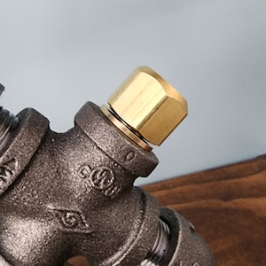 May include: Close-up of a black pipe fitting with a gold-colored cap. The fitting has a label that reads "UL" and "C911".