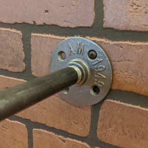 May include: A close-up of a black metal pipe fitting with a flange. The flange is stamped with the letters "AM" and the numbers "1949".