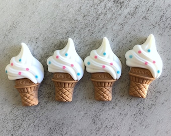 May include: Four white ice cream cones with pink and blue sprinkles. The cones are brown and have the word "Ice Crea" written on them.