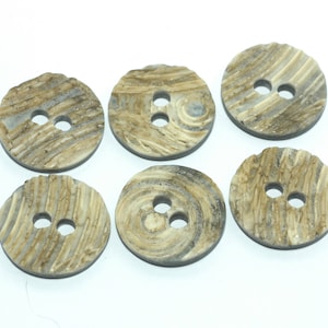 May include: Six round buttons with two holes each. The buttons have a textured, wood-like appearance with shades of brown, tan, and gray. The buttons are arranged on a white surface. Ideal for sewing and craft projects.