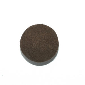 May include: A dark brown round button made of suede fabric.