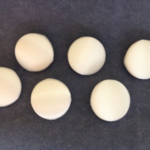 May include: Six white round buttons with a smooth, slightly shiny surface.