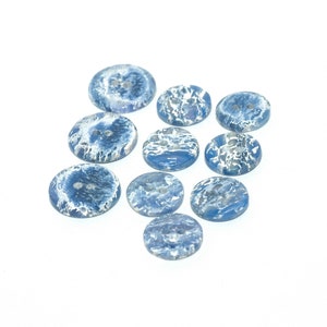 May include: Ten blue and white swirl patterned buttons. The buttons are round and have two holes.