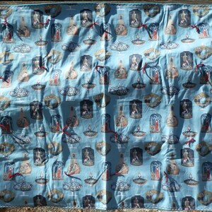 Pu&ograve; includere: Un tessuto azzurro con un motivo ripetuto di illustrazioni all'interno di vasi e cupole di vetro. Le illustrazioni presentano figure in varie pose, con nastri rossi. Il tessuto &egrave; probabilmente un tessuto decorativo.