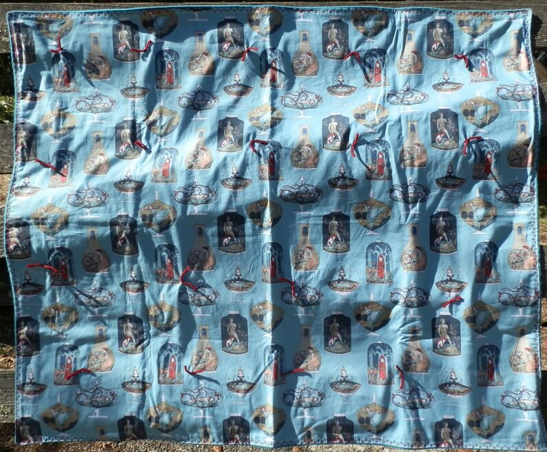 Pu&ograve; includere: Un tessuto azzurro con un motivo ripetuto di illustrazioni all'interno di vasi e cupole di vetro. Le illustrazioni presentano figure in varie pose, con nastri rossi. Il tessuto &egrave; probabilmente un tessuto decorativo.