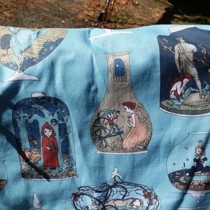 Pu&ograve; includere: Tessuto azzurro con illustrazioni ripetute di scene di fiabe all'interno di barattoli di vetro. Le illustrazioni includono Cappuccetto Rosso, sirene e altre figure fantastiche. I legami di filo rosso sono visibili sui bordi.