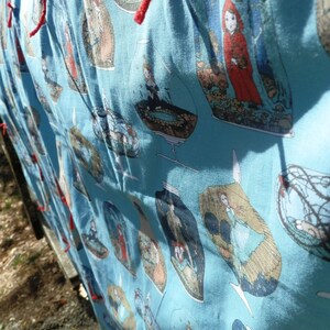 Pu&ograve; includere: Tessuto azzurro con un motivo ripetuto di illustrazioni all'interno di barattoli di vetro. Le illustrazioni presentano figure in varie scene, con lacci rossi visibili sul bordo superiore. Il tessuto &egrave; drappeggiato.