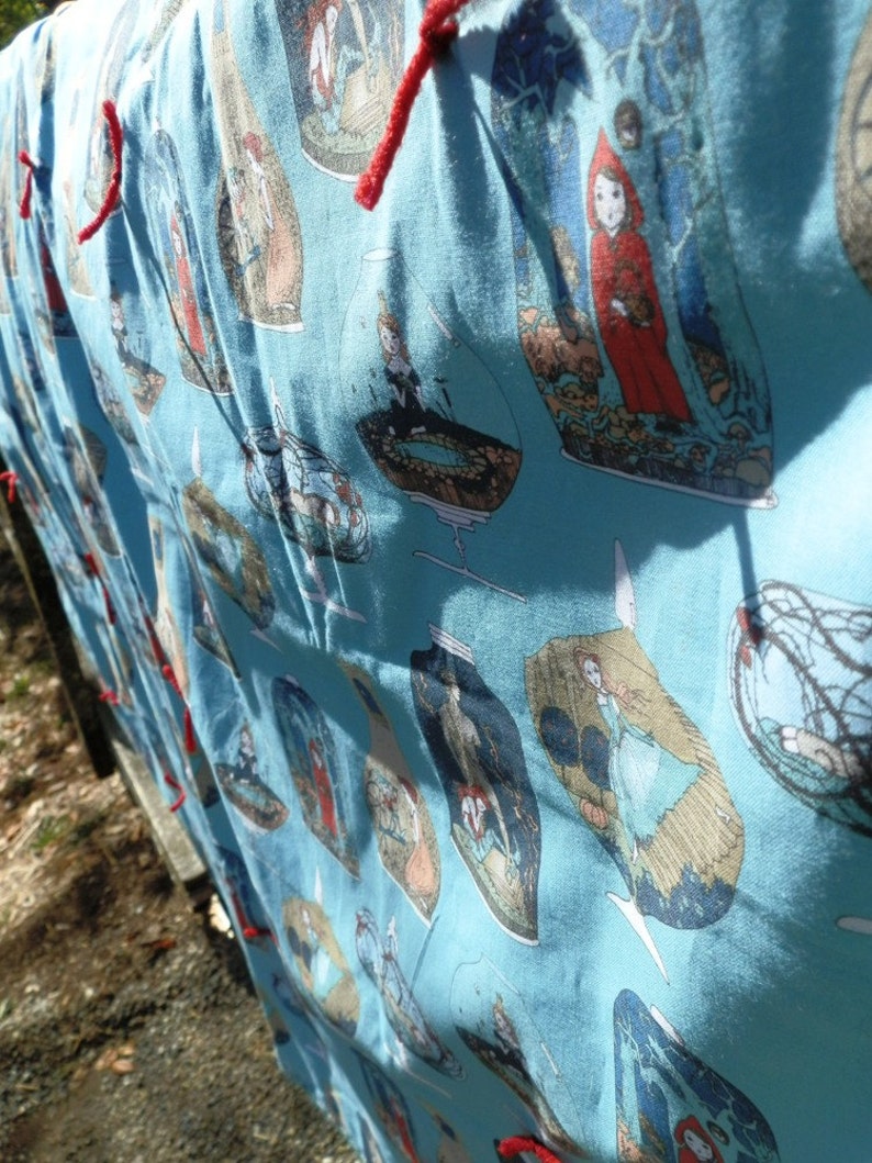 Pu&ograve; includere: Tessuto azzurro con un motivo ripetuto di illustrazioni all'interno di barattoli di vetro. Le illustrazioni presentano figure in varie scene, con lacci rossi visibili sul bordo superiore. Il tessuto &egrave; drappeggiato.