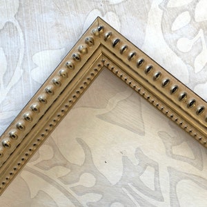 May include: A gold picture frame with a beaded edge. The frame is made of wood and has a distressed finish.