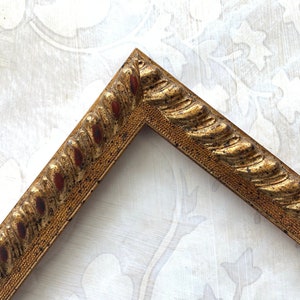 May include: A gold picture frame with a rope-like design. The frame is made of wood and has a distressed finish.