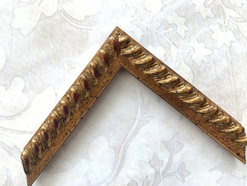May include: A gold picture frame with a rope-like design. The frame is made of wood and has a distressed finish.