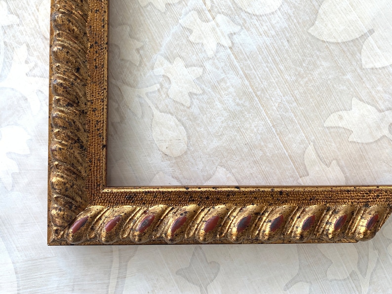 May include: A gold picture frame with a rope-like design and a distressed finish. The frame has a slightly raised edge and a subtle reddish-brown hue.