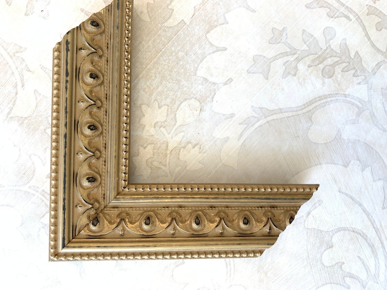 Pu&ograve; includere: Una cornice dorata con un designo decorativo ornato. La cornice ha una finitura nera e dorata ed &egrave; fatta di legno.