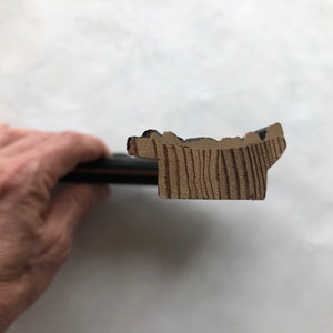 May include: Close-up of a wooden picture frame with a black painted edge. The frame has a decorative, slightly raised, scalloped edge.