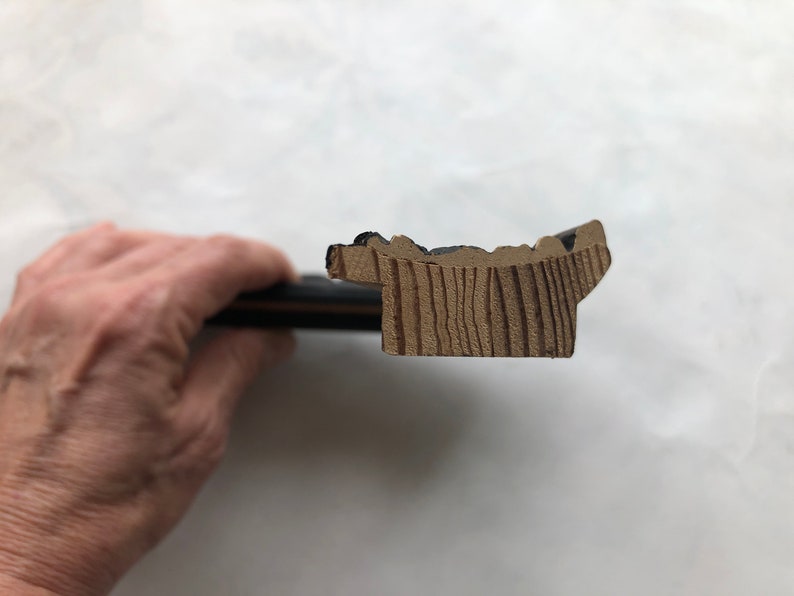 May include: Close-up of a wooden picture frame with a black painted edge. The frame has a decorative, slightly raised, scalloped edge.