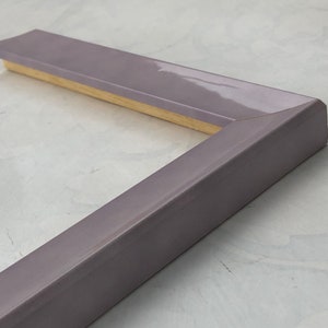 May include: A corner of a light purple picture frame with a wood backing.