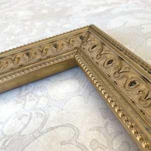 Pu&ograve; includere: Una cornice dorata con un designo ornato. La cornice ha un bordo perlato e un motivo scolpito in rilievo.