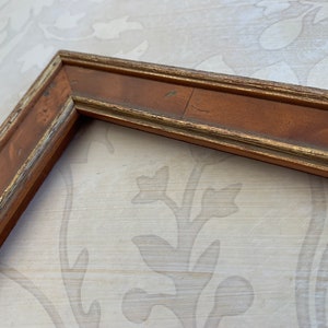 May include: A wooden picture frame with a gold trim. The frame is brown and has a distressed look.