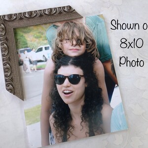 May include: A brown ornate picture frame with a photo of two people. The photo shows a woman with long curly hair wearing sunglasses and a man with long blonde hair. The text "Shown on 8x10 Photo" is printed on the photo.