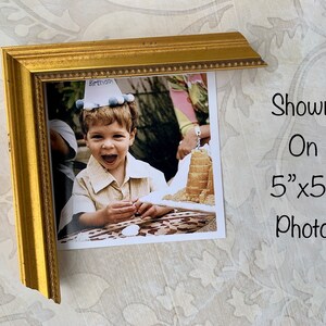 Puede incluir: Un marco de fotos dorado con una foto de 12,7 cm x 12,7 cm de un ni&ntilde;o peque&ntilde;o con un gorro de cumplea&ntilde;os. El ni&ntilde;o sonr&iacute;e y sostiene un trozo de pastel. La foto est&aacute; sobre un fondo blanco.
