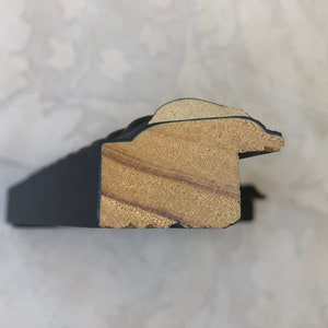 May include: Close-up of a black picture frame with a wood core. The frame has a decorative, ornate design.