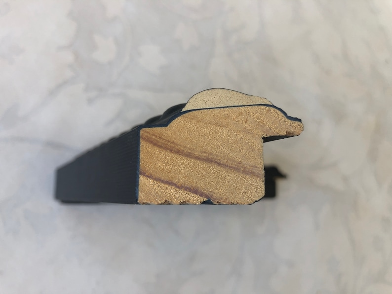May include: Close-up of a black picture frame with a wood core. The frame has a decorative, ornate design.