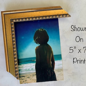 May include: A gold-colored picture frame with a beaded edge, displaying a photograph of a person standing on a beach. The text "Shown On 5" x 7" Print" is visible in the image.
