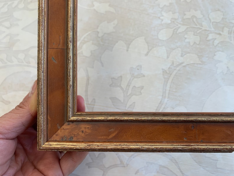 May include: A wooden picture frame with a gold trim. The frame is brown with a slightly reddish hue.
