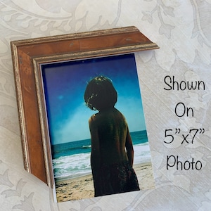 May include: A wood picture frame with a gold trim, shown on a 5" x 7" photo of a person standing on a beach.