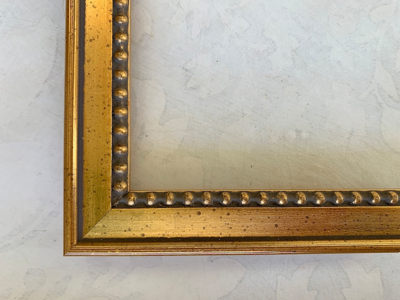 May include: A gold picture frame with a beaded edge. The frame has a distressed finish and is made of wood.