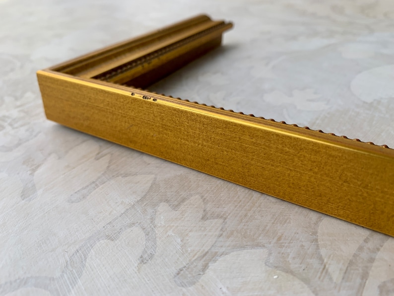 Puede incluir: Un marco de imagen dorado con un borde decorativo de cuentas. El marco est&aacute; hecho de madera y tiene un acabado mate.