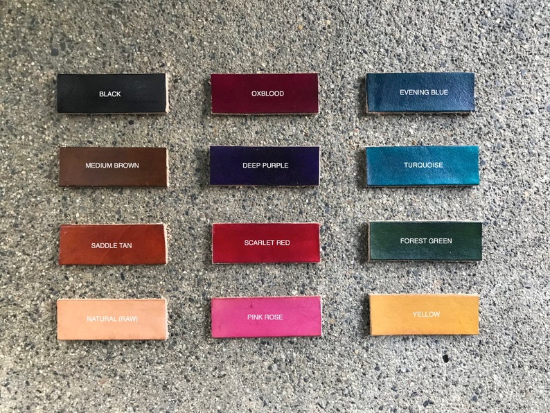 May include: A collection of rectangular leather swatches in various colors, including black, oxblood, evening blue, medium brown, deep purple, turquoise, saddle tan, scarlet red, forest green, natural (raw), pink rose, and yellow. Each swatch has the color name printed on it.